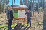 Zwei Männer vor einem Schild im Wald