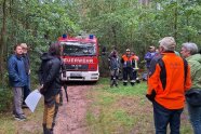 Menschen vor einem Feuerwehrauto in einem Waldgebiet