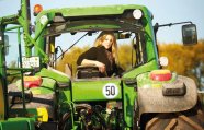 Junge Frau sitzt auf Traktor und sieht nach hinten