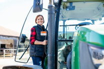 Junge Frau steigt in Traktor