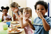 Kinder machen Brotzeit am Tisch 