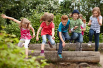 Kinder sprigen über einen Holzstamm. © Christian Schwier - fotolia.com